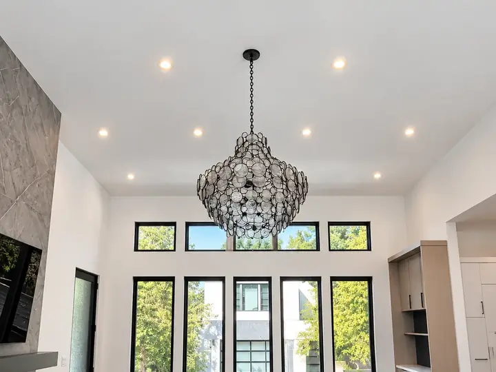 High white painted ceiling with recessed lights and a large chandelier