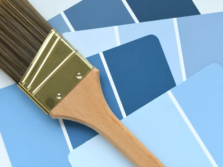 Paintbrush resting on a fan of blue paint swatches