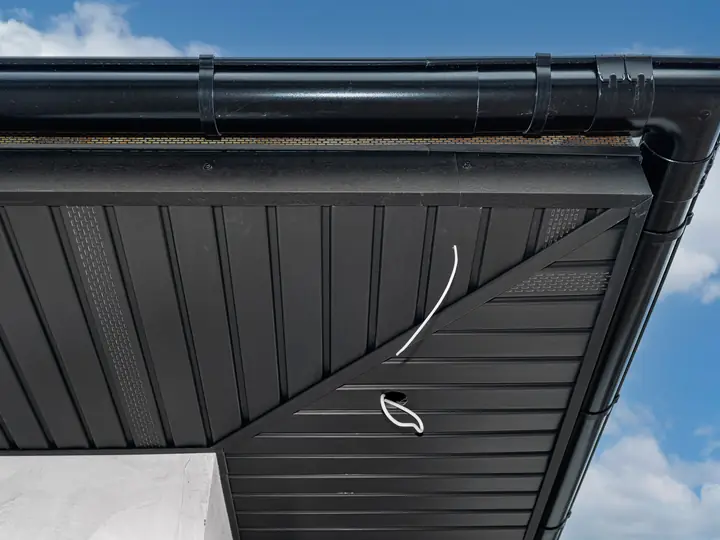 Black painted soffit, fascia and gutter against a blue sky