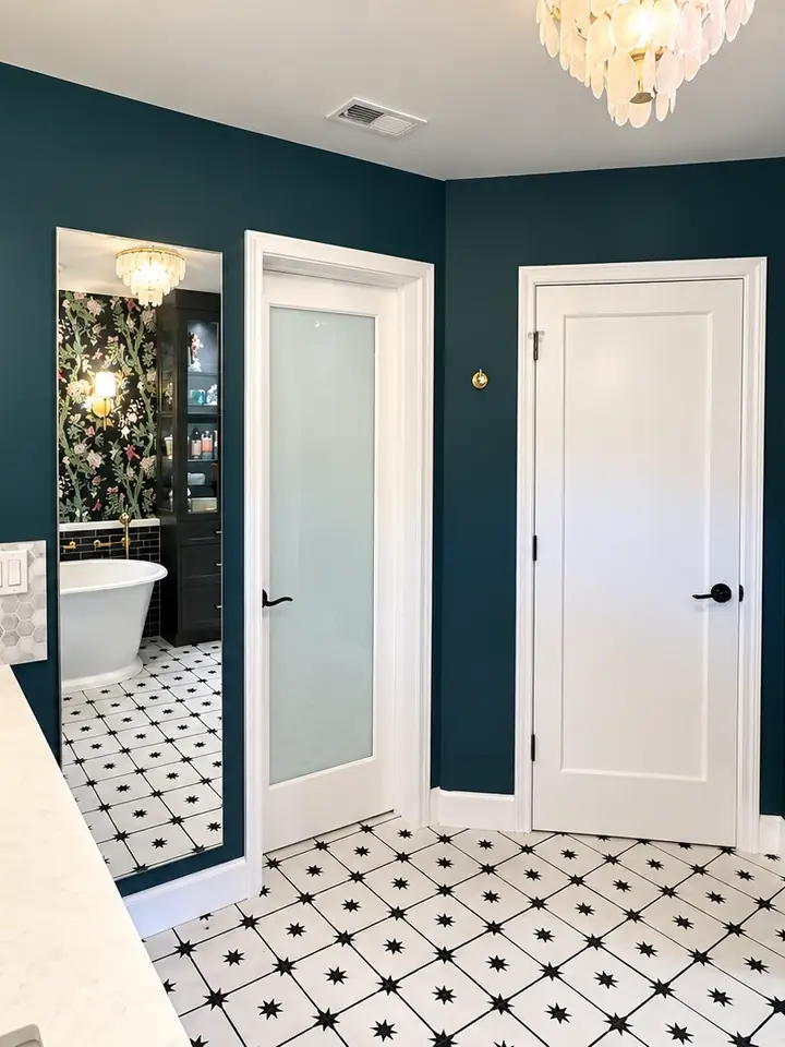 Bathroom with deep teal painted walls, crisp white doors and trim, and brass fixtures