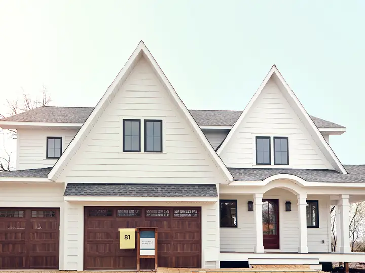 Newly built white two-story home with brown garage doors