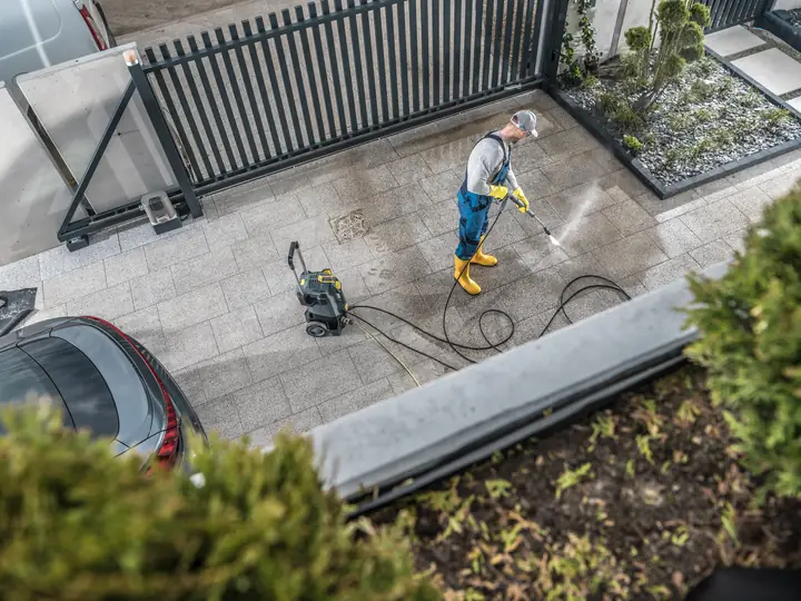 Worker pressure washing a residential driveway