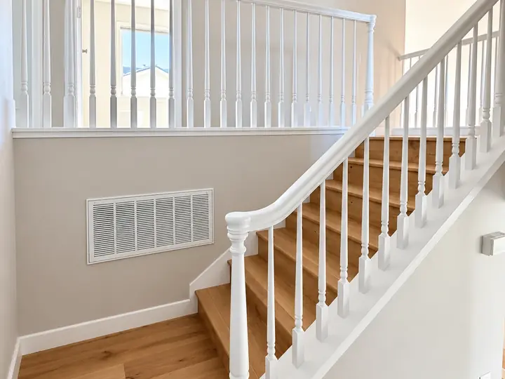 Staircase with a white painted handrail, balusters and newel post over oak treads
