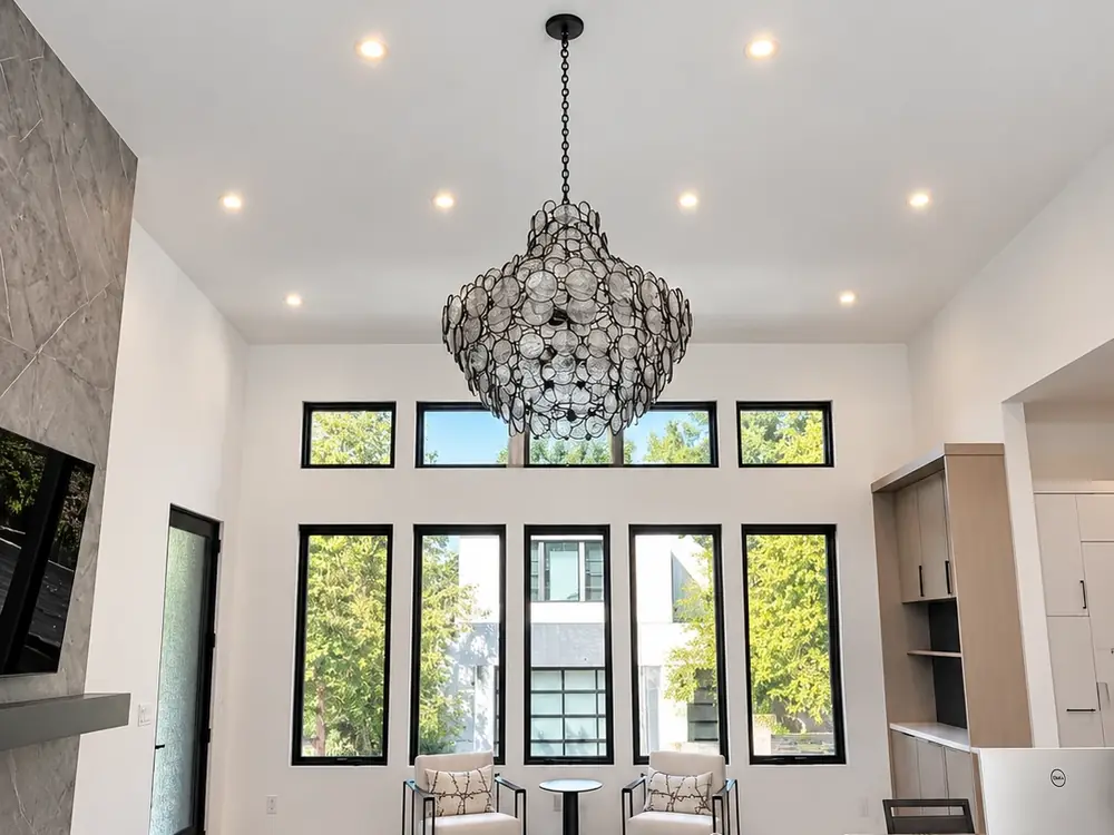 Bright great room with white painted walls and ceiling around tall black-framed windows