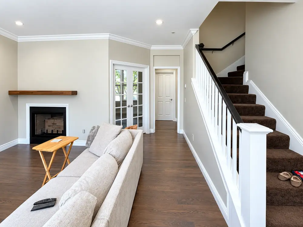 Open living room with greige walls, white crown molding and a white painted staircase railing