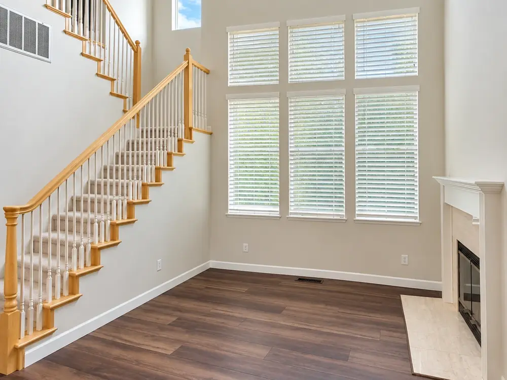 Two-story foyer with light painted walls, white baseboards and a staircase with white balusters