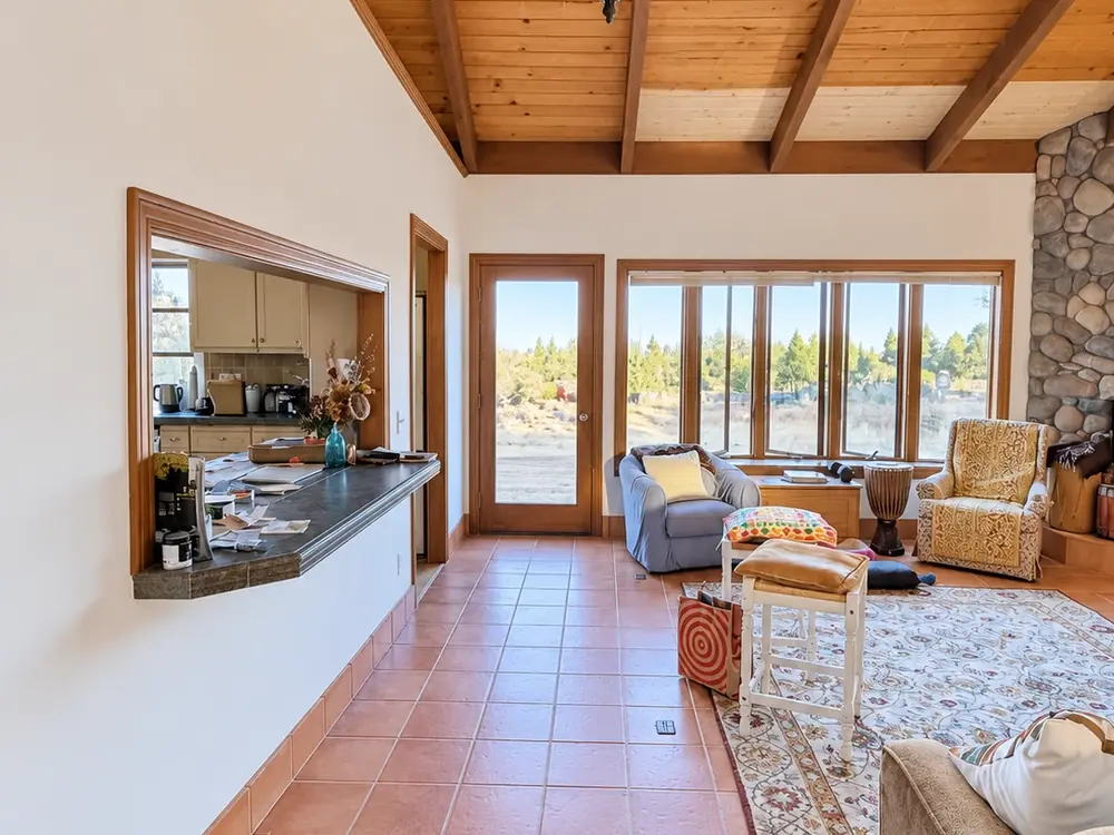 Great room with fresh white walls beneath a vaulted wood ceiling and terracotta tile floor